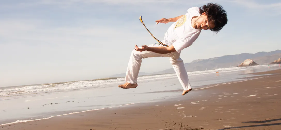 A group of capoeira practitioners performing a synchronized movement in a vibrant outdoor setting